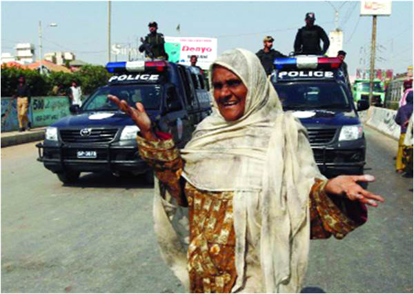 A woman shouts slogans as police vehicles watch