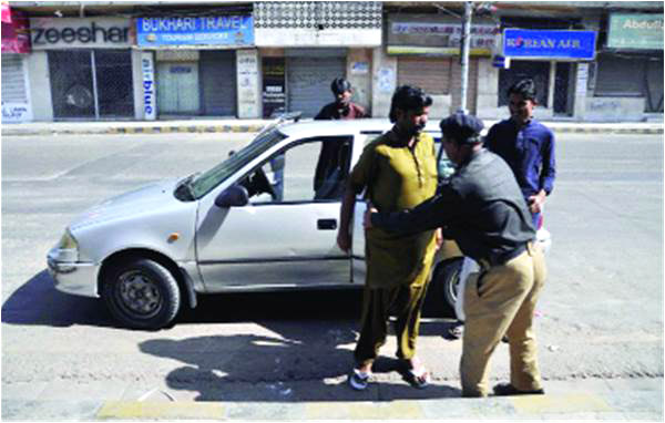 A police officer frisks a passenger at a roadside checkpoint