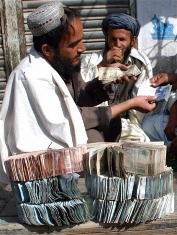 Currency exchange dealers trade Pakistani rupees and US dollars on a roadside near the Afghan border in Chaman