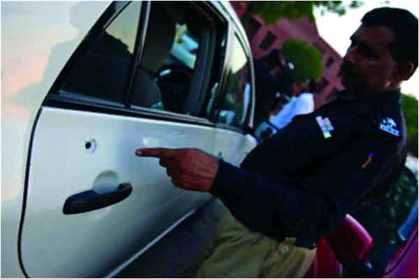 A police officer points at a bullet hole in Hamid Mir's car