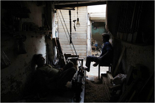Carpenters at a workshop pause during a power outage in Karachi