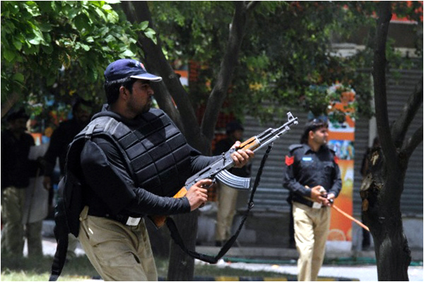 A policeman fires a gun during a clash with supporters of Tahirul Qadri in Lahore