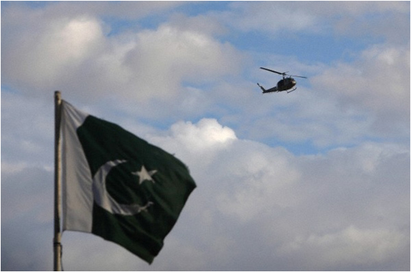 A helicopter flies past Pakistan's national flag outside the Parliament