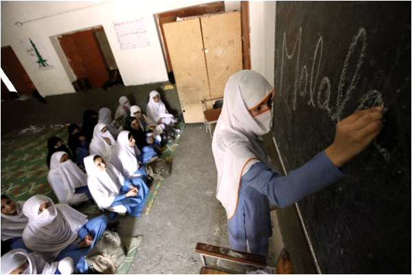 A schoolgirl from Malala's hometown Mingora writes her name on the blackboard