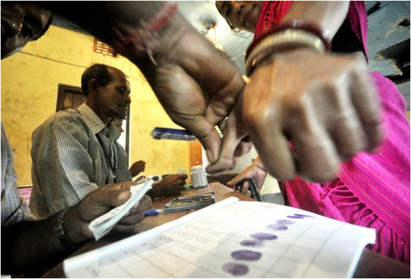 A polling official helps a voter stamp her thumb impression during the by-election in Tripura in September