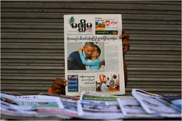 A woman shows a Mizzima newspaper with a photograph of US President Barack Obama and Myanmar pro-democracy leader Aung San Suu Kyi