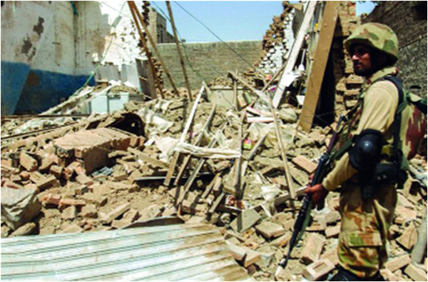 A soldier stands beside a house that was destroyed during a military operation against Taliban in the town of Miranshah