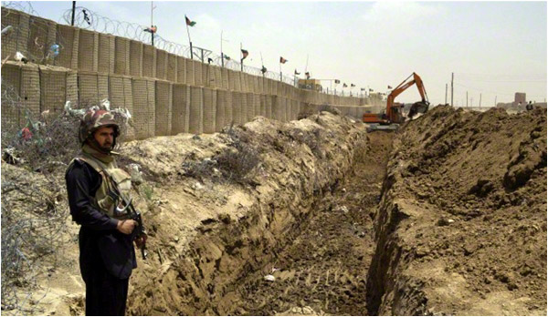 A border guard stands alert as an excavator digs a trench along the Pakistan Afghanistan border at Chaman