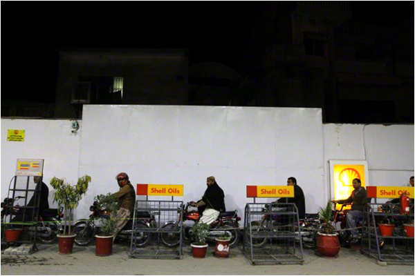 Men wait in line to get fuel for their motorbikes at a fuel station in Rawalpindi