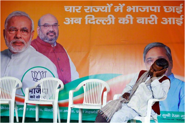 A worker of BJP takes a nap in front of a campaign billboard at a party office in New Delhi