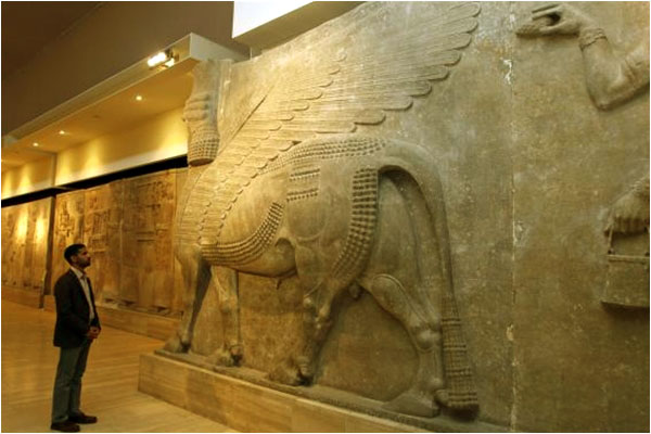 A man looks at an Assyrian relief on display in the National Museum of Iraq. How long before these too will be turned into dust?