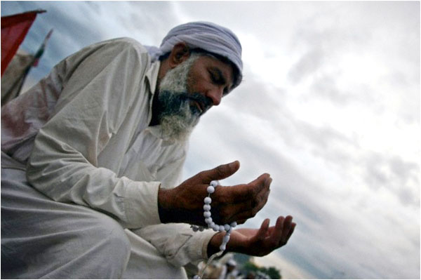 A follower of Tahirul Qadri prays in front of the parliament during the 2014 protests led by PAT and PTI