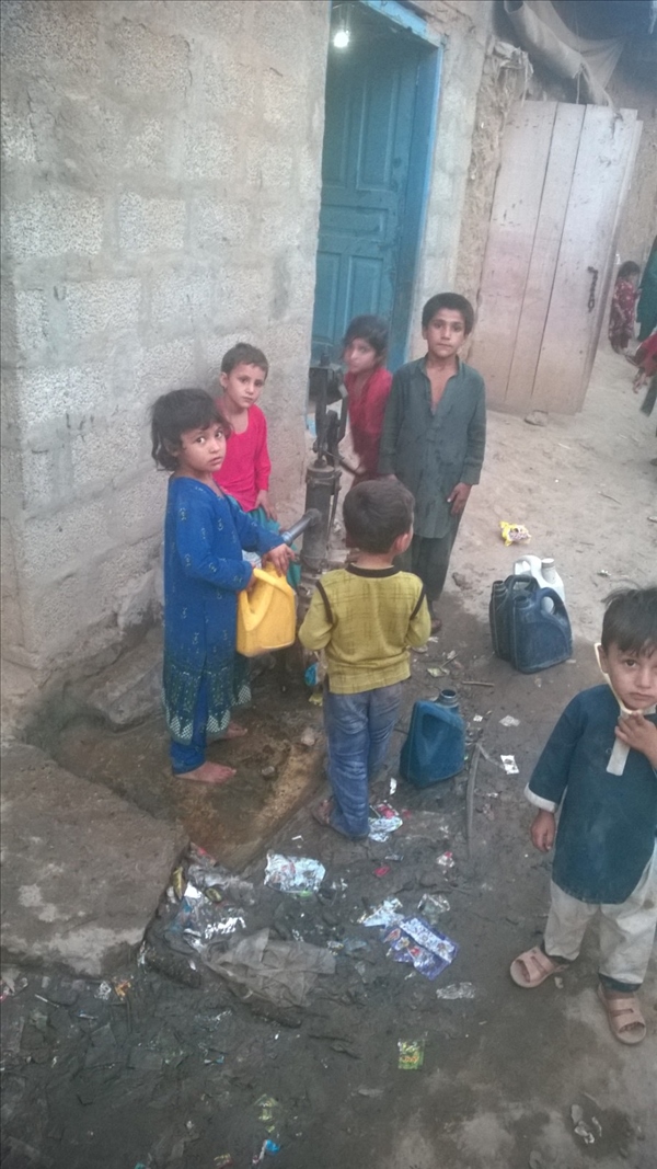 Children in the slum use a hand pump to get water