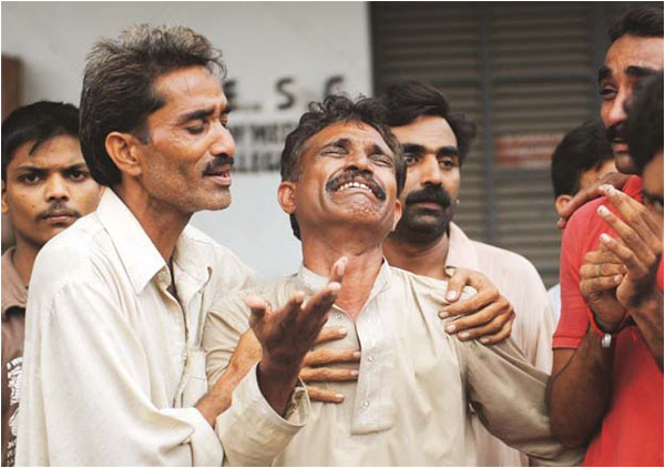 Men grieve for their relatives after Baldia Town fire incident - Photo AFP
