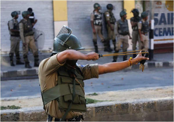 A member of the Indian paramilitary forces uses a slingshot to throw stones at Kashmiri Muslim protesters during clashes in downtown Srinagar