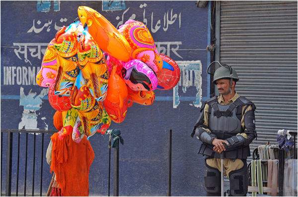 An Indian soldier in Srinagar stands guard as a Kashmiri woman passes by