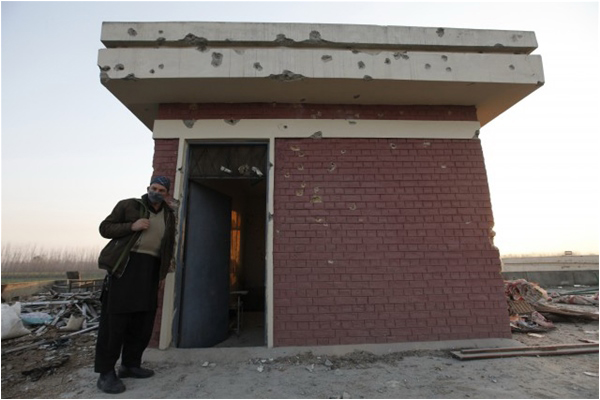 A security official stands besides a bullet-ridden building after a gunfight during the BKU attack