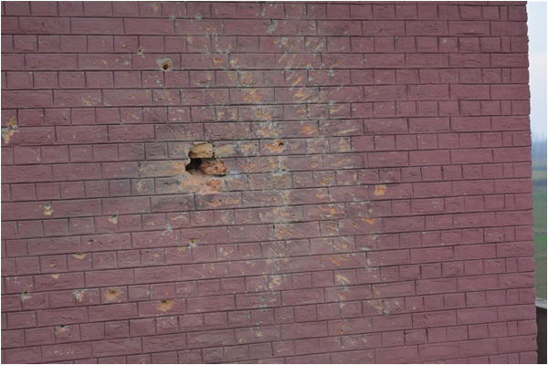 A hole left by a rocket in a wall, on campus