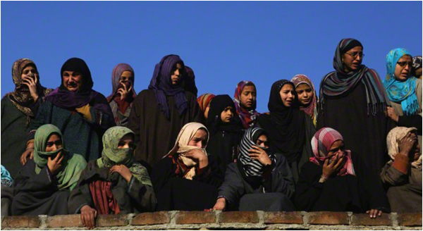Kashmiri women watch the funeral of an activist killed on February 9 during protests against the 2013 hanging of Afzal Guru