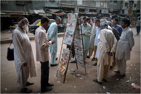 Passersby reading the front page of Janbaz on March 2, 2015 in Agra Taj Colony, Lyari. Credit: L. Gayer